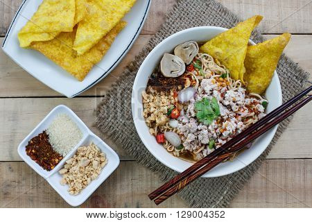 Spicy instant noodle soup with minced pork on wood background Top view