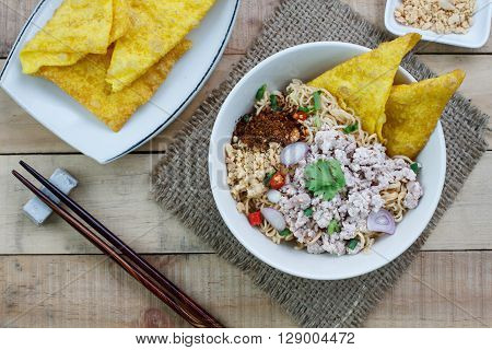 Spicy instant noodle with minced pork on wood background.Topview