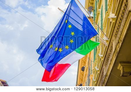 FLORENCE, ITALY - JUNE 12, 2015: Europe Union flag in blue color with yellow stars representing the countries that are in, behind Italy flag.