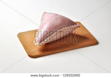 Triangular salami in pork rind on cutting board