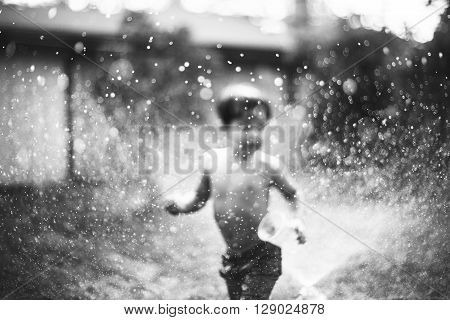 A Little Boy Running Around The Puddles