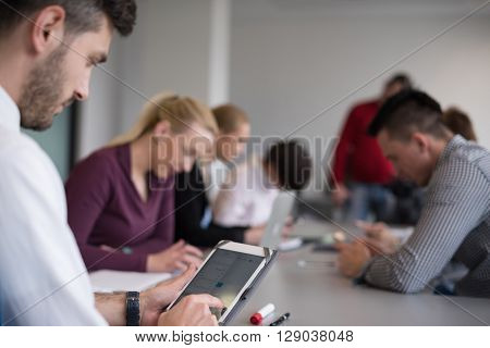 close up of  businessman hands  using tablet, people group in office meeting  room blurred in backgronud
