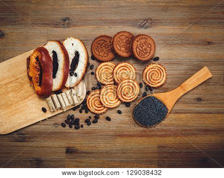 There are Pieces of Roll with Poppyseed,Cookies Halavah Chocolate Peas, Tasty Sweet Food on the Wooden Background,Top View,Toned