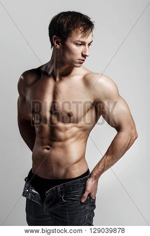 Muscular Male Model Bodybuilder With Unbuttoned Jeans. Studio Shot On Gray Background. Fitness Model