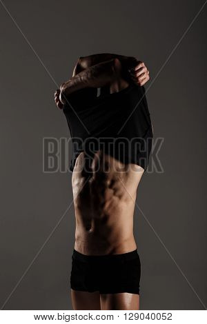 Muscular Male Model Bodybuilder After Training Remove T-shirt. Studio Shot On Gray Background. Great