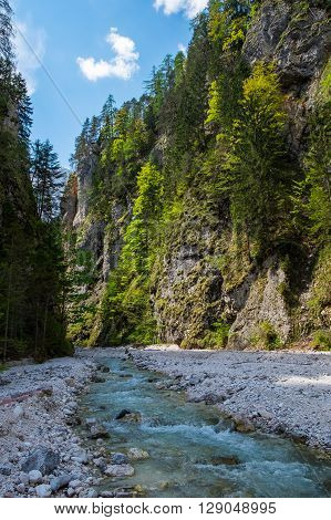 Mountain fast river stream in the rocks. Canyon with creek under blue sky.  Pebble shore of brook.