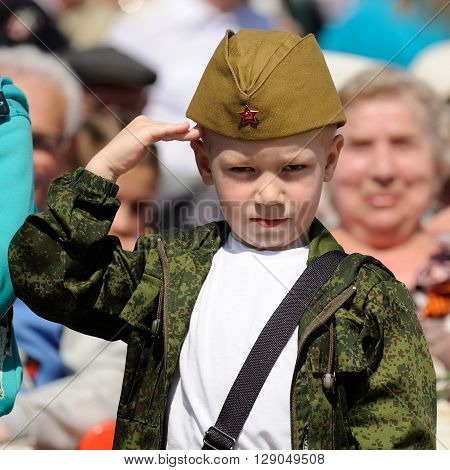 Orel Russia - May 9 2016: Celebration of 71th anniversary of the Victory Day (WWII). Little boy saluting in Russian military field cap closeup