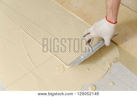 Laying plywood on the floor. A worker puts glue for gluing of the plywood