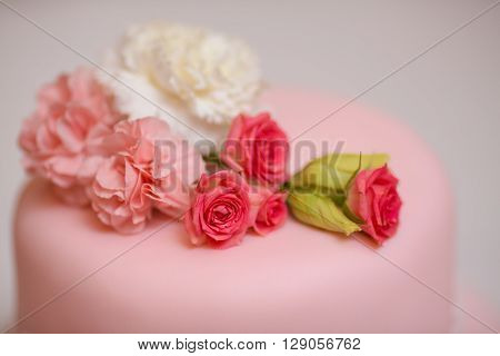 Close-up pink wedding cake with roses against  copy space background
