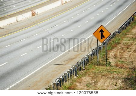 merge sign by the side of multi-lane highway