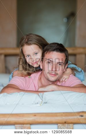 Man with little kid sitting in bed smiling