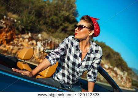 Beautiful pin up woman sitting in cabriolet enjoying trip on luxury modern car with open roof fashionable lifestyle concept