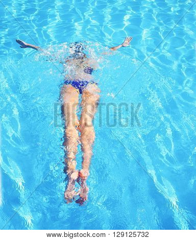 Young woman swimming in a blue water of swimming pool. Underwater swimming