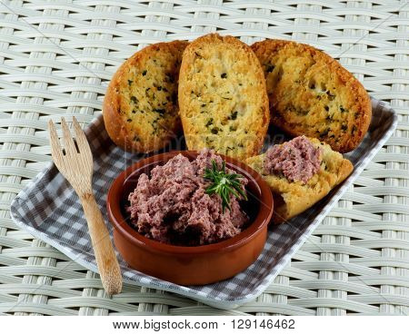Delicious Homemade Meat Pate with Crispy Herbs Bread in Checkered Tray closeup on Wicker background