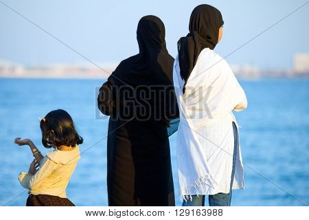 Doha Qatar - April 10 2006: Women in traditional dress looking at the sea from the La Corniche waterfront