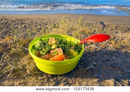 Dish with unusual vegetarian salad on the beach. Healthy eating while traveling hiking. Sunny day on Cyprus.