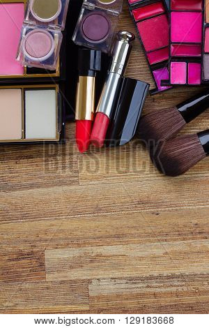 set of  brushes, lipsticks, maskara, eye shadows with copy space on wooden table
