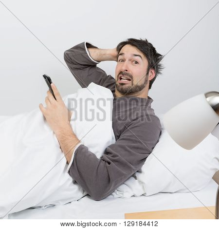 man with beard lying in a bed with white bedding