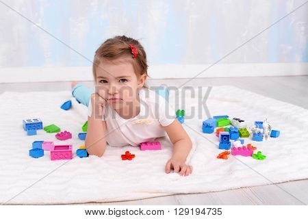 Frowning ?hild girl playing with toys constructor