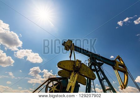 Oil and gas well profiled on blue sky with cumulus clouds