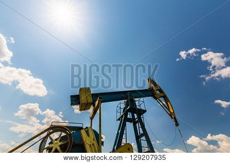 Oil and gas well profiled on blue sky with cumulus clouds