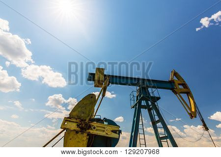 Oil and gas well profiled on blue sky with cumulus clouds