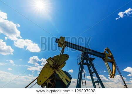 Oil and gas well profiled on blue sky with cumulus clouds