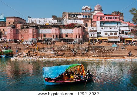 MADHYA PRADESH, INDIA - DEC 27, 2012: Beautiful indian city with old brick houses river ghat and blue color boat on water on December 27, 2012 in Chitracoot. Population of Chitrakoot is 22294 people.