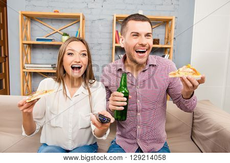 Atractive Happy Young Man And Woman Watching Tv With Beer And Pizza