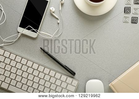 Workplace with mobile phone, peripheral devices and stationery on grey table