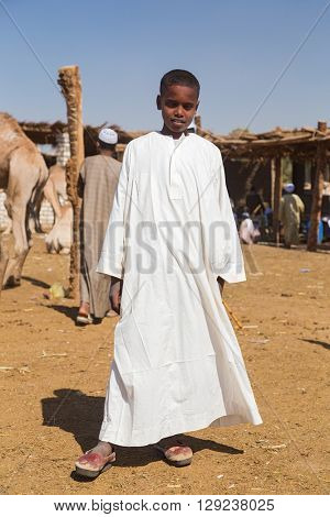 DARAW, EGYPT - FEBRUARY 6, 2016: Local young camel salesmen on Camel market in white robe posing for camera.