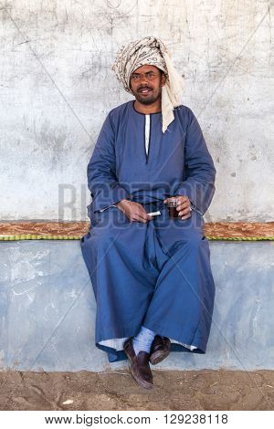 DARAW, EGYPT - FEBRUARY 6, 2016: Local camel salesman holding glass and cigarette.