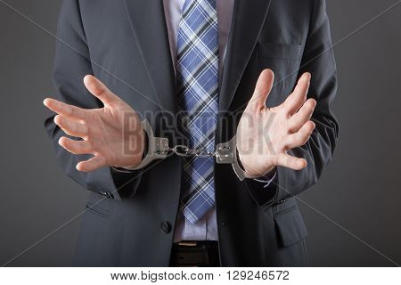 businessman in handcuffs arrested isolated on grey background