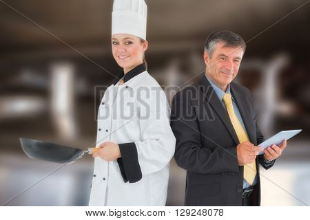 Businessman holding digital tablet and chef with frying pan against large vats of beer