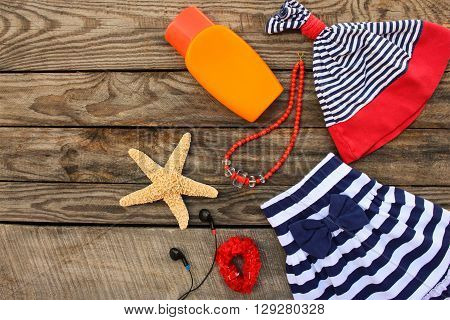 Summer children's clothing and beach accessories for your sea holiday on the old wooden background. Toned image.