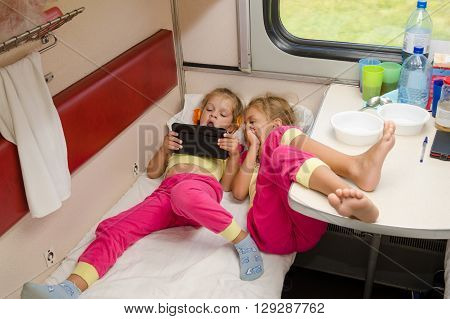 Two Little Girls Lie On The Train With His Feet On The Lower Second-class Place Car In The Same Paja