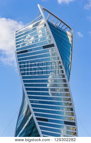 Moscow, Russia - April 23, 2016: Header of the Evolution Tower in the business complex Moscow City with blue sky and reflection of city and clouds in mirrors