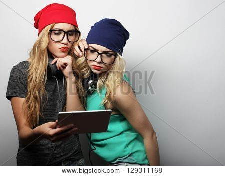 two hipster girls friends use digital tablet, studio shot over gray vackground