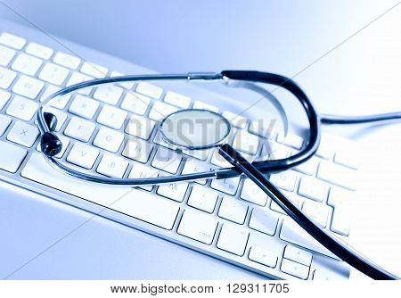 Computer keyboard and medical stethoscope, studio shot. Research or technical support theme.
