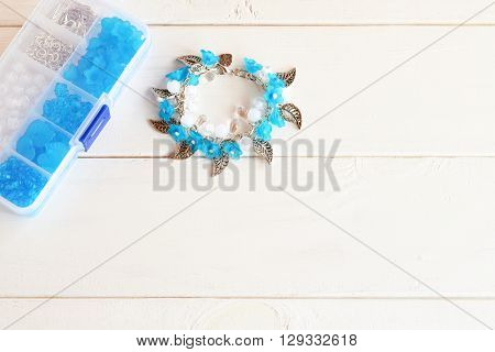 Bracelet with flowers, beads and metal pendants. Organizer with accessories for making jewelry.