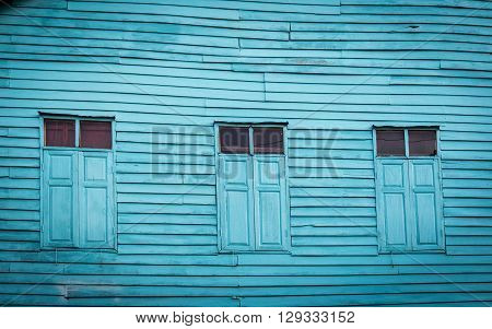 Three Windows on old wooden house Painted bright blue