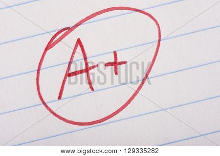 A plus (A+) grade written in red pen on notebook paper.