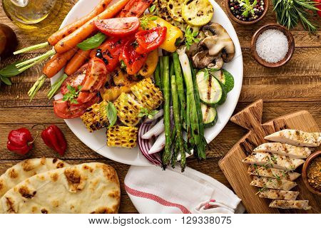 Grilled vegetables and chicken on wooden table overhead shot