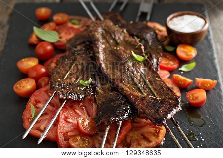 Flank steak on skewers with tomato salad