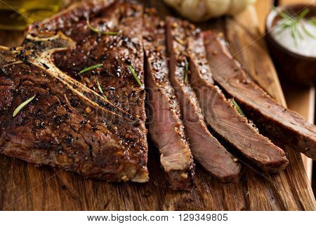 Tbone beef steak cooked on a grill with rosemary and garlic