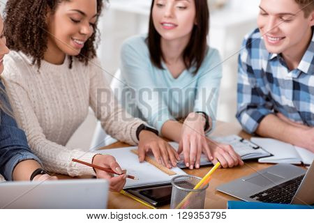 Using my lineal. Cheerful and concerned students sitting together in the circle and working during their studying