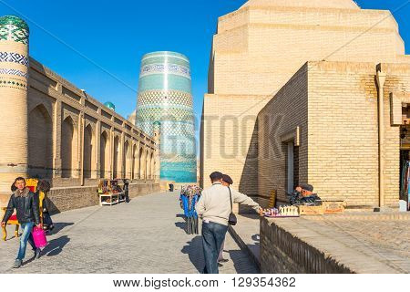 Khiva Uzbekistan - Aprilr 15 2014: Local people in the country center with the Kalta Minor minaret and Muhammad Amin Khan Madrassah