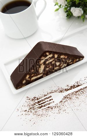 Chocolate cake white coffee cup fork shape white flowers green leaves over head shot