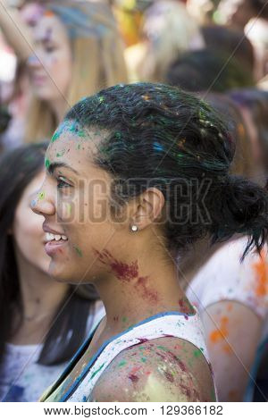 NEW YORK - APR 30 2016: A woman in the crowd with colorful powder on her face celebrating the Holi Hai Festival of Colors hosted by NYC Bhangra in New York on April 30 2016.