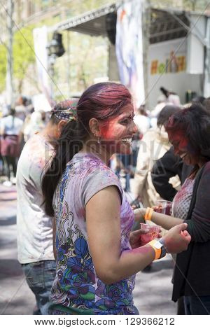 NEW YORK - APR 30 2016: A woman in the crowd with colorful powder on her face celebrating the Holi Hai Festival of Colors hosted by NYC Bhangra in New York on April 30 2016.